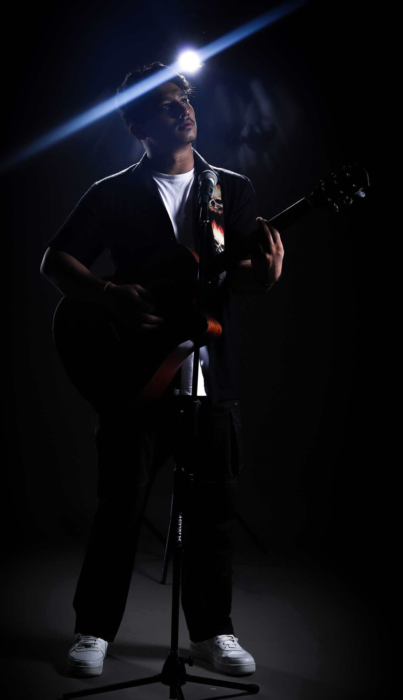 Aman Karki performing with guitar under studio spotlight